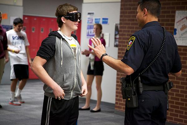 Dec. 19, On-campus school officer Ricky Jimenez explains to junior Kyle Ash how wearing the fatal vision googles impairs your vision and how standardized field sobriety test works in science teacher Susan Shepperds forensic science class. Photo by Rowan Khazendar.