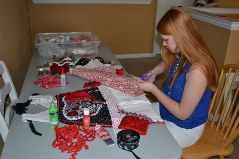 Junior Olivia Brooks cuts out letters and matches fabric for her senior overalls.