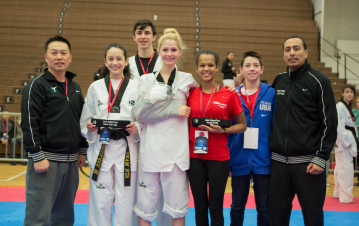 Following the final matches of a day of competition at the 2014 Team Trials in Colorado Springs, three Coppell taekwondo athletes pose with Master Sang Cha (left) after a long day of sparring. New Tech freshman Trinity Sullivan, CHS junior Connor Wilson, CHS sophomore Madison Giddens, taekwondo competitor Kelsey Junious, 8th grader Connor Giddens and Juniouss coach Alvaro Mendez (right) come together for a victory group shot. Photo courtesy of Madison Giddens.