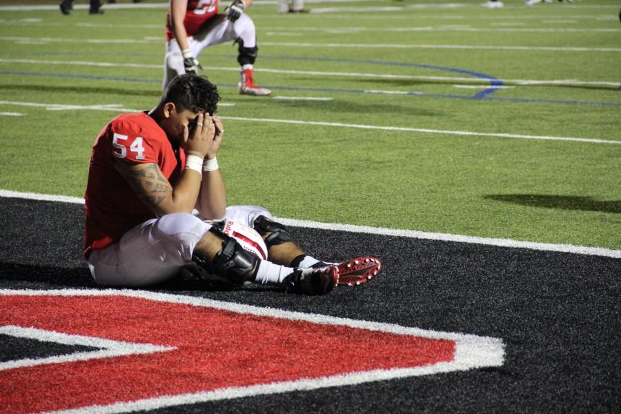 Coppell High School senior Matt Rockefeller takes a seat on the end line after losing to Coppell’s rivals the Southlake Dragons. After the double over-time Southlake managed to keep up the hard work resulting in a 38-37 defeat over Coppell Friday night at Buddy Echols Field. Photo by Megan Winkle.