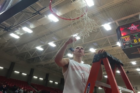 Senior guard Josh Fink cuts down the net after the Cowboys win in the first game in their new arena. Fink, who has been a part of the program for four years, was one of the seniors honored before the game in the senior night festivities.