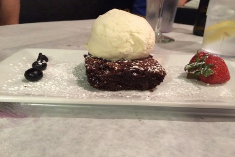 Flourless chocolate brownie served under a scoop of vanilla ice cream with berries.