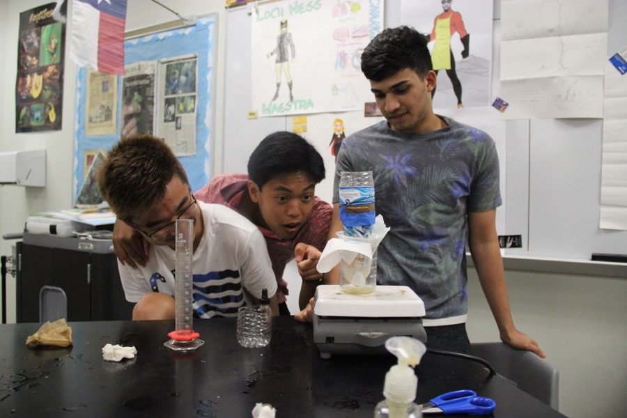 Coppell High School juniors Brian Pak, Micah Abaya, and Sahil Kacherikar watch as their wastewater gets filtered through layers of sand, rocks and dirt in Holly Anderson’s AP Environmental Science class on Friday. AP Environmental Science is currently working on a “Wastewater Treatment Lab” with the intention of cleaning a sample of wastewater. 