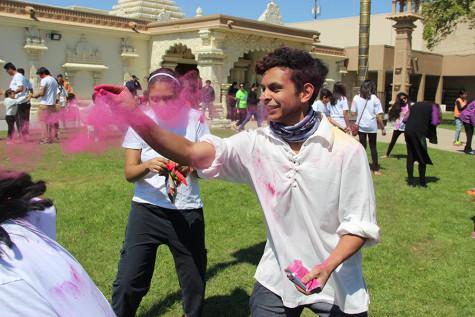 Coppell High School senior Asu Dhakal throws the his first magenta Holi powder of the day on Sunday at the at the DFW Hindu Temple. “[My first Holi experience] has been so much fun, it’s so crazy and completely unlike anything else,” Dhakal said.
