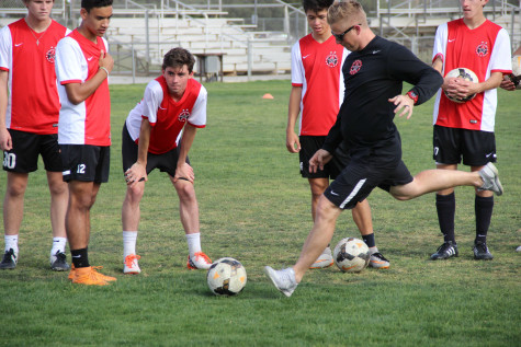 In Coppell’s practice on Thursday, April 7, coach Chad Rakestraw takes a penalty kick as the team looks on. Rakestraw has led this team to a 20-0-2 record thus far and their second regional tournament berth in three years.