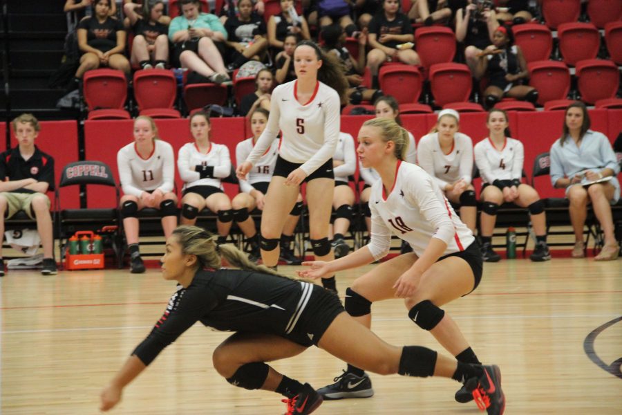 Coppell High School senior libero Lauren Lee dives to save the ball from hitting the ground while junior defensive specialist Izzy Hall and junior outside and rightside hitter Amanda Colon try to rush to her aid at the varsity game against W.T. White Tuesday night in the arena. Photo by Hannah Tucker.