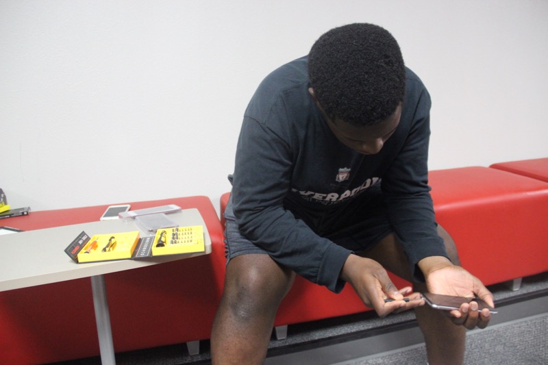 Coppell High School junior Dennis Onalaja fixes a client’s phone during school. Onalaja taught himself how to fix phones and now has a business called Revival. He is also starting a club where he takes old or broken phones, repairs them and gives them to the less fortunate. 
