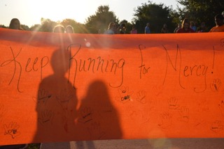 Two children stand behind a banner for Mercy at a run in her memory on Saturday, September 26, 2015 at Andy Brown East. The Mercy Run helped raise money to support children who have lost a sibling. Photo courtesy of Allison D’Auteuil.
