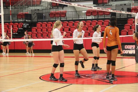 Coppell High School senior outside and right hitter Grace Heaton laughs as she stretches out her legs to begin playing again at the varsity game against W.T. White Tuesday night in the CHS arena. Heaton, member of the varsity team, plays the position of outside and right hitter. Photo by Hannah Tucker.