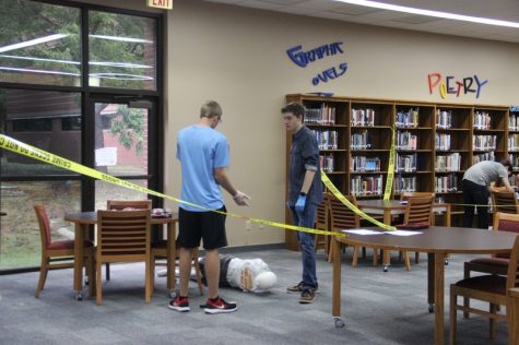 Coppell High School seniors Ryan Moscati and Aaron Smith talk about the crime scene and the clues to what happened to the body on the floor on Monday during teacher Sandy Kirkpatrick’s third period forensics science class. Students studied the crime scenes and used them to help write their conclusions for the lab in the library. 