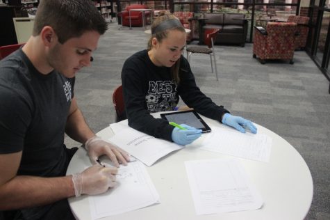 Coppell High School seniors Baylee Hux and Michael Otto work on their diagram and chart for forensic science Monday morning in the library. Students studied the crime scenes and used them to help write their conclusions for the lab. 