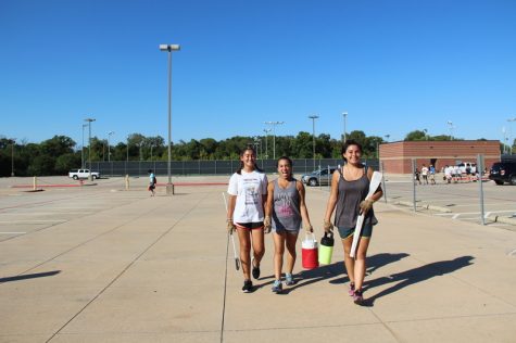 Coppell High School juniors Melissa Medel and Isabella Cantu and sophomore Delaney Bell walk to after school band practice in the parking lot behind Buddy Echols Field on Wednesday afternoon. All three are veteran members of the Coppell Color Guard and are used to this daily rehearsal routine. Photo by Hannah Tucker.