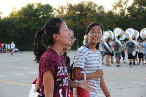 Coppell High School band participants (left to right) senior Hana Choi, junior Tanya Kiatsuranont and sophomore Kei Mashimo chat and start to walk back to the band hall to put away their instruments after Wednesday evening’s practice. All three are flutists, and each one has a specific spot that they march in for the halftime show. Photo by Hannah Tucker.