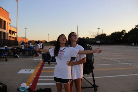 Coppell High School junior trumpet player Julia Holloway and sophomore trumpet player Natalia Routhier reenact the Titanic scene while goofing around after cleaning up in the parking lot Wednesday evening. Each section of the band has different unique personalities, and the trumpet section is no exemption from this statement. Photo by Hannah Tucker.