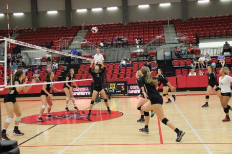 Coppell High School sophomore Stella Yan sets the ball as teammates run to spike it over the net during the homecoming game Friday night in the CHS arena. The Cowgirls won 3-0 against the J.J. Pearce Mustangs, remaining undefeated in the district with a 6-0 district record. 