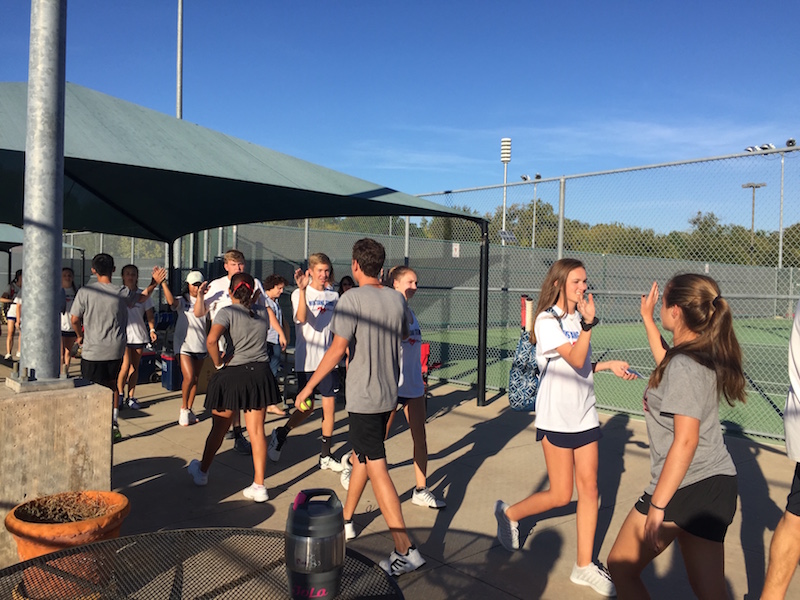 Coppell High School varsity tennis players exchange high-fives with Pierce High School players after winning 10-0 on Oct. 21. The Cowboys will advance to regionals, hoping to continue their winning streak