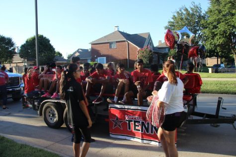 Coppell High School tennis team members sit around waiting on their float near Cottonwood Creek Elementary at the parade after school on Wednesday. While some of the students rode on the float, others walked alongside passing out school colored beads. Photo by Hannah Tucker.
