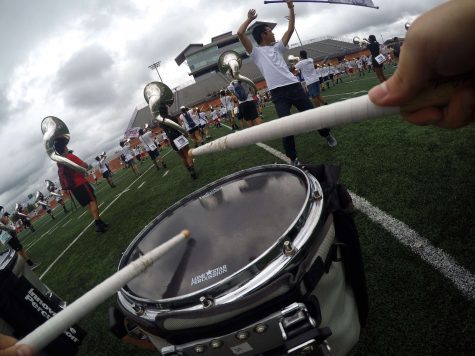 The Coppell Band practices before the UIL State competition at Heroes Stadium in San Antonio on Nov. 8. Rehearsing the first movement of the show, “Rose Colored Glasses,” senior snare drummer Eliana Yamouni attaches a GoPro to her drum harness to get an on-field level view. Photo by Hannah Tucker.