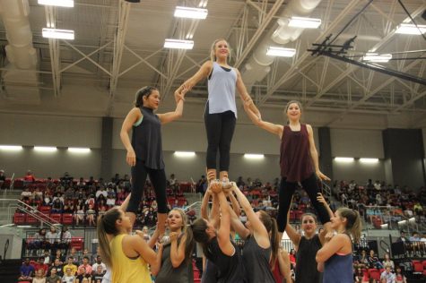 Coppell High School senior varsity cheerleaders Julie White, Avery Mullins and Makenzie Dennis are lifted into the air by their teammates during their senior cheer routine in the arena last Friday. Each group of seniors in the fall sports put on a performance at the senior pep rally. Photo by Hannah Tucker.