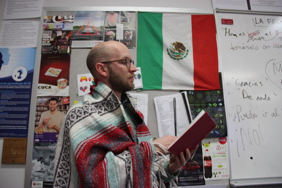 Coppell High School IB Spanish teacher Creighton Hulse shows off his blanket from Mexico in front of the Mexican flag hanging in his room. Hulse has taught in many different countries and uses his experiences to help teach students at Coppell.
