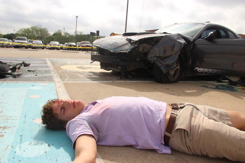 Coppell High School senior Eric Loop lays injured on the ground after being thrown from a car during a drunk driving accident simulation in the CHS parking lot last Thursday for the Shattered Dreams presentation. Loop was thrown from the car during Coppell’s biannual Shattered Dreams, a presentation put on by KCBY which reproduces the possible outcomes of a DWI crash in hopes to prevent teenage drinking and driving. Photo by Hannah Tucker.
