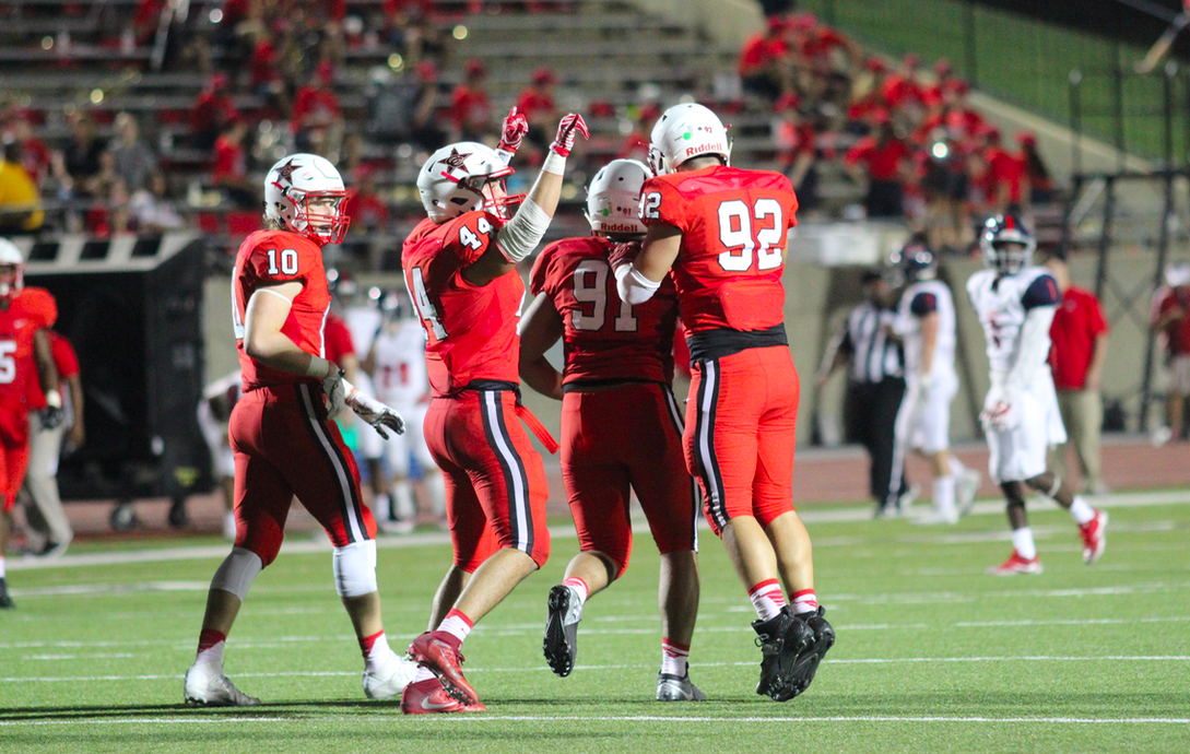 Coppell High School junior Joseph Sheddy congratulates senior KK Moe for making a good tackle, as senior Pierce McFarlane celebrates with the crowd. The Coppell Cowboys played against McKinney Boyd at Buddy Echols Field last night and came out with a win, 34-24.