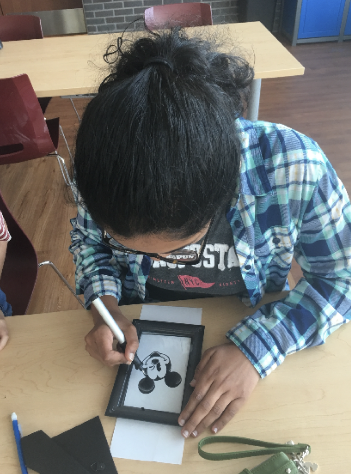 Coppell High School senior Carol Varghese engraves Mickey Mouse on a piece of glass on Monday at the Coppell Cozby Library. Varghese enjoys the true precision needed to create art.