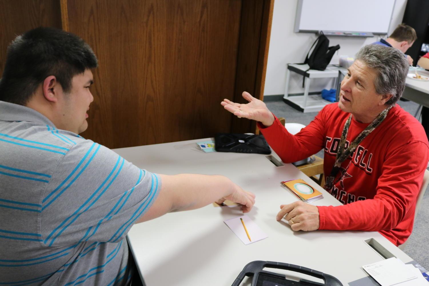 Coppell+High+School+student+Nathaniel+Umlas++learns+Intensive+Teacher+training+%28ITT%29+cards+with+special+needs+teacher%2C+Ed+Beal%2C+in+the+new+education+room+D101.+Beal+moved+his+special+needs+classroom+from+C+hall+to+D+hall+this+school+year+for+a+more+spacious+and+accessible+learning+room+for+students.+%0A