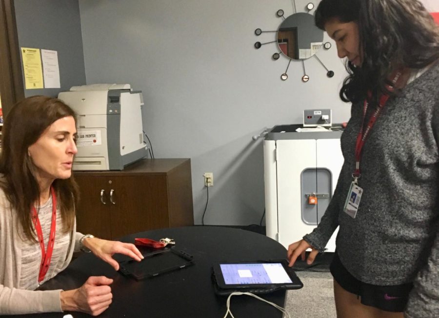 Coppell High School  campus technology aid Susan Whiting assists senior Brissa Nino as she turns in her iPad during eigth period in the downstairs blended lab. Seniors are required to turn in their issued iPads in order to graduate.