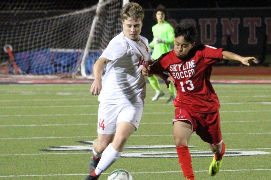 Coppell High School senior defender Thomas Grimmer runs with the ball alongside Skyline junior midfielder Edgar Munoz during the first half of the game on senior night March. 20. The Cowboys won the game against the Raiders 6-0.
