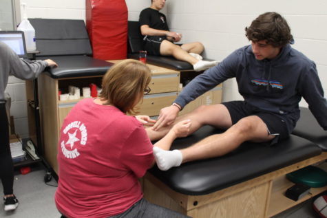 Coppell High School freshman track runner  Zach Stricker talks with Coach Yevtte Carson about his leg Monday morning in the athletic trainers room. Athletes are encouraged to talk to the trainers about any issues regarding their physical health.