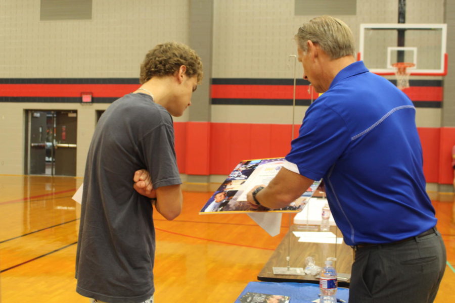 Coppell High School junior Johan Pretorius listens to Jason Oswald from the United States Coast Guard about the requirements and opportunities he can earn from this program. Oswald uses a pamphlet to explain these details. 