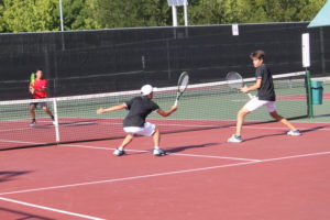 Coppell High School varsity tennis player junior Mihiro Suzuki and freshman Andreja Zrnic dive to hit the ball during their second set against Marcus High School on September 18. Suzuki moved to Coppell from Japan before his sophomore year of high school and has found a home on the tennis team.