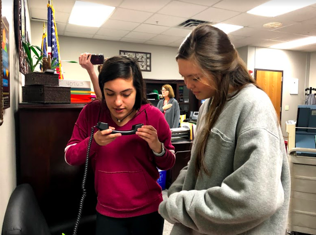 Coppell High School Red Jacket seniors Jimena Benavides and Addison Sork announce the pledges over the intercom during seventh period in the administration office. Red Jackets announce pledges everyday during third/seventh period. Photo by Nevaeh Jones. 