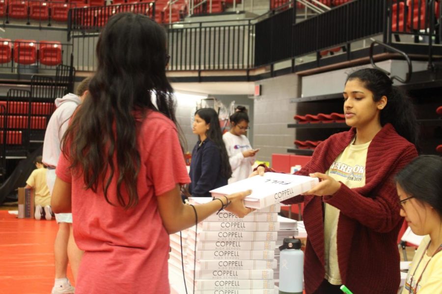 Coppell High School junior Anais Hartley receives her Round-Up yearbook today during sixth period. The yearbook pick up will be held at the Arena all throughout the day at Coppell High School for CHS students. Photo by Laura Amador-Toro