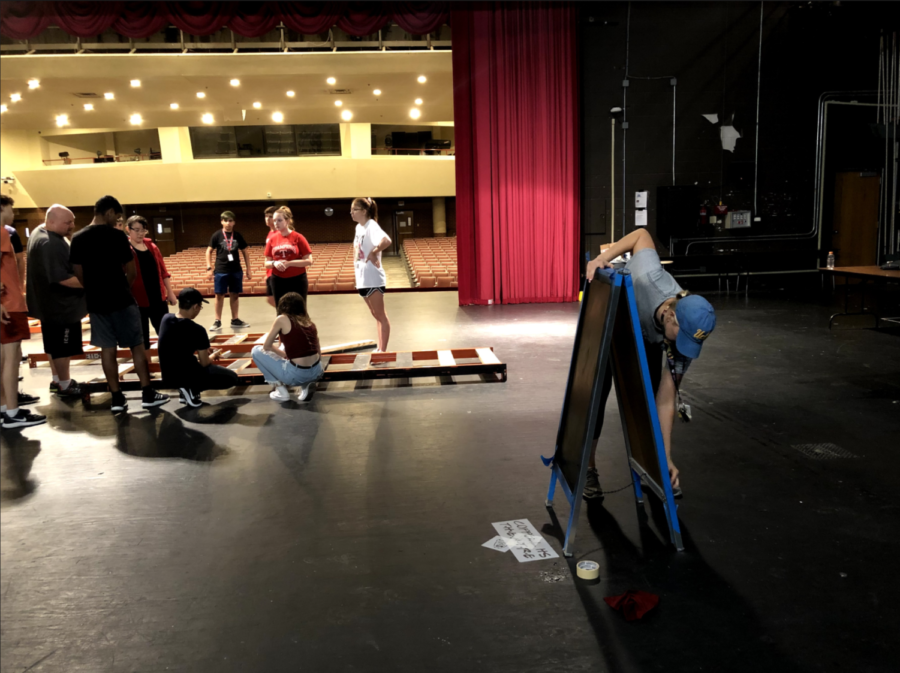 Coppell+High+School+theater+department+head+Karen+Ruth+cleans+a+sign+for+%E2%80%9CNewsies%E2%80%9D+on+the+CHS+Auditorium+stage+while+theater+students+finalize+props.+The+show+runs+from+Nov.+1-3%2C+9+and+10+in+the+CHS+Auditorium.