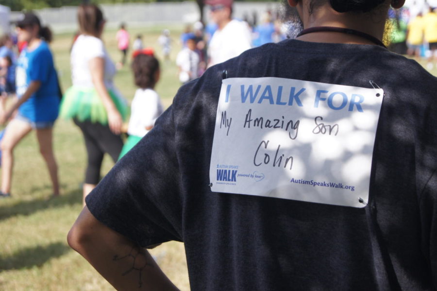 Walkers wear signs on their backs, showing who they are walking for during the Autism Speaks Walk at the Campus at Legacy in Plano on Saturday. Many people do this to show their support for the autism community and their family. Photo by Sneha Sash