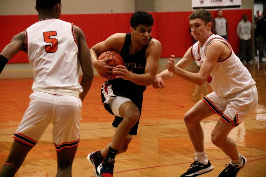 Coppell senior guard Adam Moussa attempts to break through two of Rockwall’s defenders on Nov. 22 in the CHS gym during the Classic Chevrolet Coppell Showcase. The Cowboys came out on top by defeating Garland, 76-40, Lamar, 65-61, Rockwall, 61-30 and Bishop Lynch, 72-40, but lost to Ellison, 63-60.