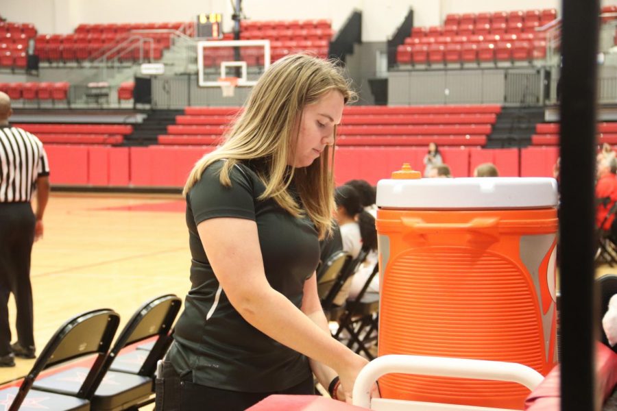 CHS/Coppell junior sports medicine trainer Taylor Evans fills water bottles for players at the varsity girls basketball game against Grapevine on Dec. 10 at the CHS Arena. Evans works exclusively with basketball during the winter season.
