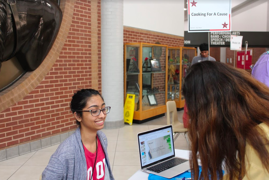 Coppell High School senior Cooking For A Cause co-President and co-founder Pragati Mundhada signs up a new member at the club expo during C-lunch on Oct. 4, 2019. Cooking For A Cause members make food for events and charities.