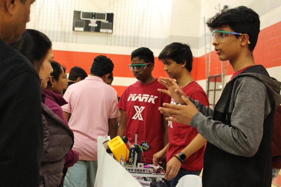 Mark X Robotics club leaders junior Aryan Damle and two other Coppell ISD students tell parents more about their club in the CHS9 small gym at the Spring Showcase. The annual event took place from on Jan. 27 and allowed incoming freshmen and their parents to tour the campus and learn about course and extracurricular opportunities. 