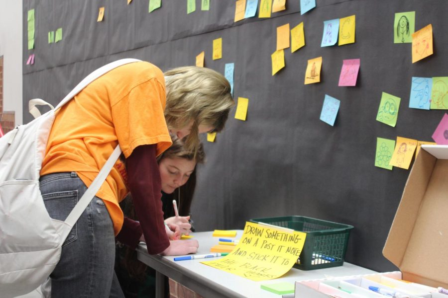 Coppell High School sophomore Rowan Reese and junior Sadie Harp draws on a sticky note during B lunch in the Large Commons on Thursday. Students in National Art Honor Society throughout the day orchestrate art activities during all lunches today.