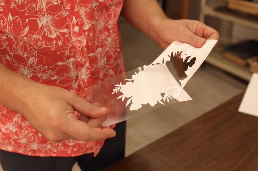 Coppell High School sculpture and AP 3D art teacher David Bearden peels away the untouched vinyl in his classroom on Wednesday. Bearden held a mask design contest and CHS senior Roshni Patel’s mask won and will be sold at CHS.
