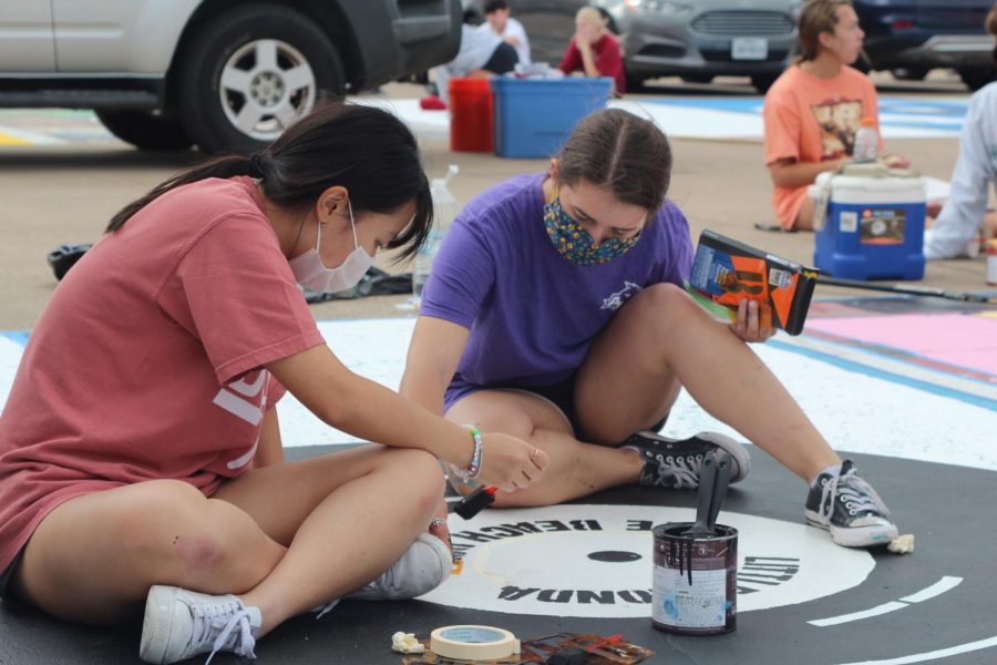 Coppell High School seniors Denise Kim and Olivia Palmer paint details on Palmer’s parking spot on Oct. 17 at CHS. Senior parking spot painting allows students to express their creativity through this CHS tradition despite the pandemic.