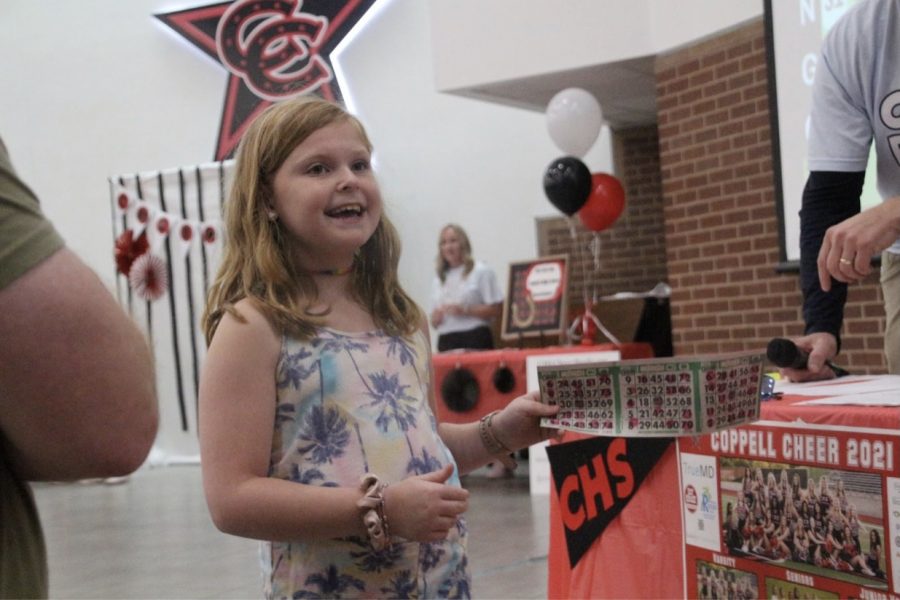 Presley Kryzak, cousin of Coppell High School senior Katy Kryzak on the varsity cheer team, holds up her bingo sheet in pure bliss as she gets a bingo. On Oct 24, CHS cheer team hosted their annual fundraiser Cheer Bingo at 2-4 p.m. after a two-year wait. Photo by Jayden Chui.