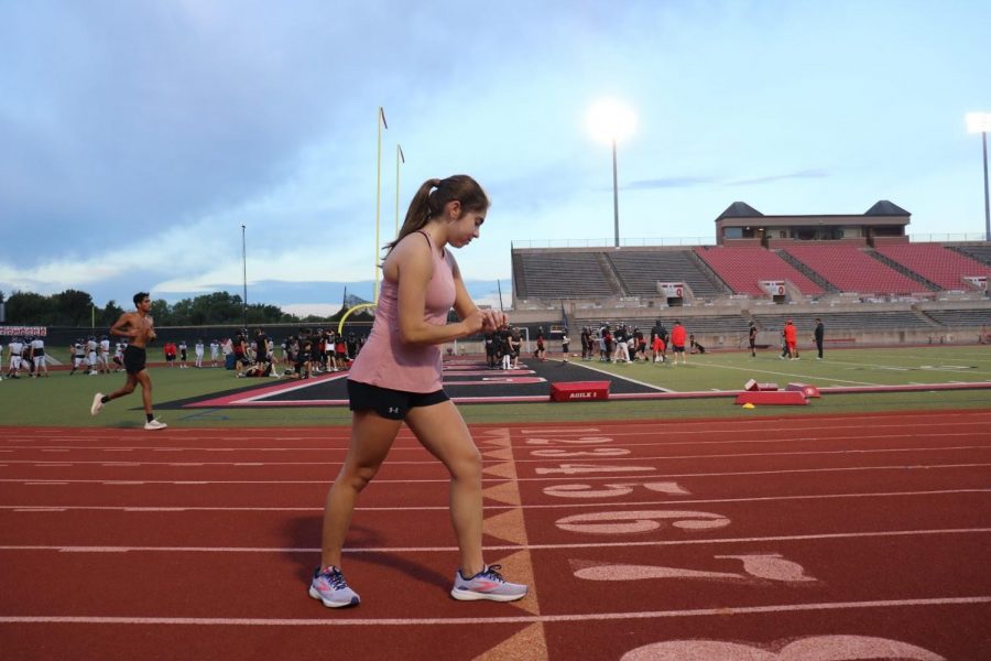 Coppell High School senior runner Izzy Ortigoza sets up her stopwatch during cross country practice at Buddy Echols Field on Oct 16. Ortigoza is on the junior varsity cross country team and is a coach at Texas Dreams Gymnastics.