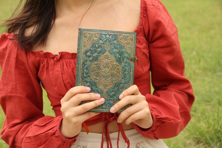 Coppell High School senior valedictorian Mira Jiang holds her personal journal where she writes down new book ideas. Jiang is a novelist, musician and dancer as well as a philanthropist.