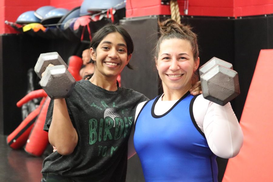 CHS9 varsity wrestler Ishitha Mallidi and Coppell High School girls wrestling coach Maxine Lisot pose with dumbbells at the CHS Fieldhouse on Sept. 22. Mallidi has been wrestling for three years.