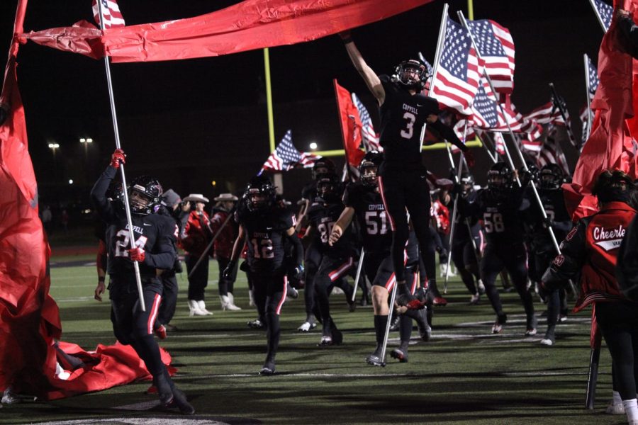The Coppell football team runs through a banner prior to the game against McKinney at Buddy Echols Field on Nov. 11. McKinney defeated Coppell, 44-26, in the Class 6A Division II Region I bi-district playoffs.