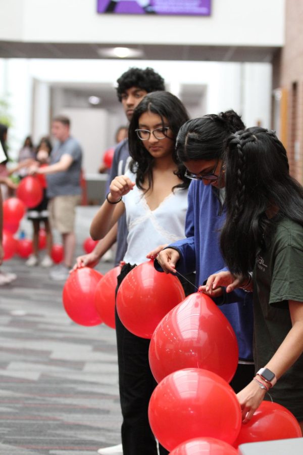 Coppell High School Student Council juniors Smera Dasgupta, Aditri Chikkam and Sanika Patil string red balloons into garlands for Red Ribbon Week in front of the library on Oct. 21. StuCo is implementing a new vision during the 2022-23 school year that promotes student engagement in events and activities through decorations, spirit days and more.